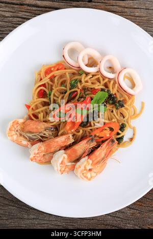 Gebratene, scharfe Spaghetti mit gemischten Meeresfrüchten und Kräutern auf weißem Teller, thailändische Küche Stockfoto