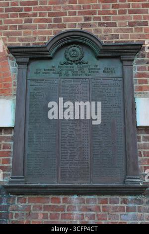 Diese kunstvoll verzierte Metalltafel, die an einer roten Backsteinmauer am Standort des Haslar Hospital befestigt ist, ehrt die Mitarbeiter des London County Council, die während des Ersten Weltkriegs in der Marine und im Militär gedient haben. Die Plakette ist mit einem Wappen gekrönt und mit klassischen Details eingerahmt und listet Namen in strukturierten Säulen auf – jede davon ist ein stiller Beweis für Dienst, Opfer und bürgerliches Gedächtnis. Sie verankert das institutionelle Erbe des Ortes in der nationalen Geschichte. Illustratives, redaktionelles Bild, Besuch des ehemaligen Krankenhauses Haslar in Gosport, Hampshire, England. August 2025. Stockfoto