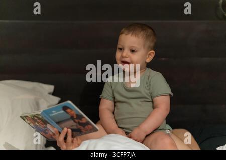 Ein entzückendes männliches Kleinkind spielt mit seiner Mutter nicht weit weg. Stockfoto