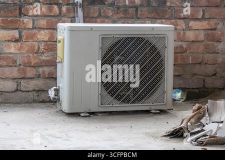 Weiße Klimaanlagen-Kompressoreinheit auf einem Dach eines Wohnhauses, ein Symbol für moderne Kühlung und Komfort. Stockfoto