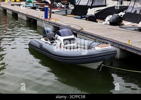 Kleines Rib-Boot, Pontonboot, Schnellboot auf einem See, vor Anker am Pier Stockfoto