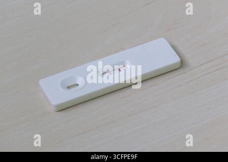 Luteinisierendes Hormon (LH) Testkit mit positivem Ergebnis mit zwei Linien auf Holzhintergrund. Dieser Heim-Ovulationstest hilft Frauen, ihre M zu identifizieren Stockfoto