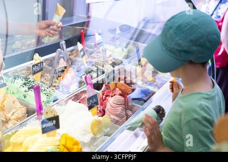 Kind wählt Eisgeschmack aus einer farbenfrohen Eispräsentation in einer Eisdiele Stockfoto