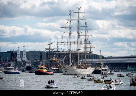 Amsterdam Niederlande 24. August 2025 das Finale des fünfjährlichen Sail Tall Ships-Events ist das sogenannte Sail-Out. Der het ij Wasserweg im Zentrum von Amsterdam ist ein Block mit kleinen Booten, während die großen Schiffe ihren Weg zum Noordzeekanaal und danach zur Nordsee machen. Aufgrund des Westwindes und der Westrichtung halten viele der Schiffe ihre Segel gerollt. Der Shabab Oman II führt den Weg. HAVEN, Sail25, People, Niederländisch, Nederland, Holland, Besucher, Stockfoto