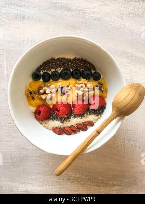 Gesunde Frühstücksschale mit bunten Früchten, Samen und Holzlöffel. Leckere Idee für das morgendliche Essen aus griechischem Joghurt, Chia Stockfoto