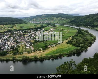 Spektakuläres Landschaftsfoto Mosel, die sich in grünen Weinbergen dreht, Landschaft und kleine Stadt Pünderich, gut besuchte Touristenattraktion Stockfoto