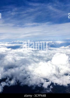 Ein vertikales Foto mit Blick auf den Himmel über Wolken mit einem blauen Himmel weißen Wolken. Flauschige weiße Wolken am sonnigen Tag von oben. Stockfoto