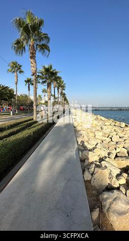Moderne Strandpromenade mit Palmen und einer Promenade, die in Richtung der Skyline der Stadt Limassol auf Zypern führt. Stockfoto