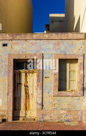 Altes Steingebäude mit abgenutzten Türen und Fenstern in hellem Sonnenlicht Stockfoto