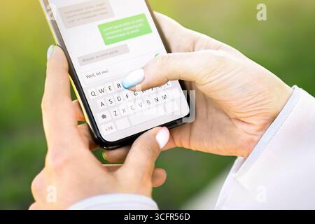 Textnachricht mit Telefon. Betrug oder Betrug mit sms auf dem Smartphone. Datum mit mobilen Welsen. Frau, die Sofortchat nutzt. App-Tastatur zur Hand. Stockfoto