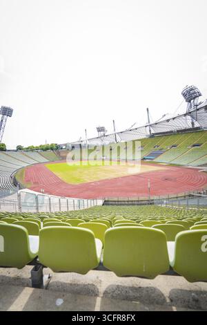 Blick auf ein leeres Stadion mit grünen Sitzen und roter Laufbahn, Olympiapark, München, Deutschland Stockfoto