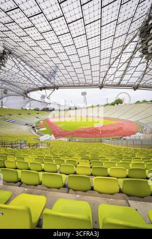 Panoramablick auf das Stadion mit gelb-grünen Sitzen und roter Laufbahn unter einem filigranen Dach, Olympiapark, München, Deutschland Stockfoto