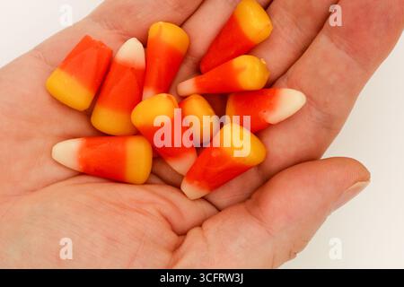 Nahaufnahme einer Hand, die Halloween-Bonbons in Form von Maisbonbons hält Stockfoto