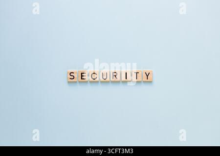 Das Wort SICHERHEIT auf einem wunderschönen blauen Hintergrund. Flache Ladefläche, Kopierraum. Ein Symbol für Sicherheit und Schutz. Ein Sicherheitssymbol auf Holzblöcken Stockfoto