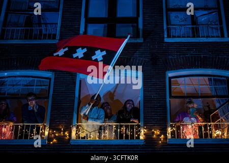 Amsterdam, Nordholland, Niederlande. August 2025. Während der Schließung des Prinsengracht-Konzerts 2025 schwenkt ein Einwohner von Amsterdam die Flagge der Stadt Amsterdam. Am 23. August 2025 feierten die Niederlande ihr 44. Jährliches klassisches Open-Air-Konzert im Pulitzer Hotel. Diese kostenlose Veranstaltung findet seit 1981 jedes Jahr statt, selbst während der COVID-Pandemie. (Kreditbild: © James Petermeier/ZUMA Press Wire) NUR REDAKTIONELLE VERWENDUNG! Nicht für kommerzielle ZWECKE! Stockfoto