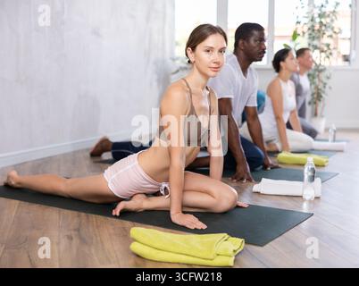 Sportliche Menschen verschiedener Nationalitäten üben Yoga-Unterricht im Sportclub Stockfoto
