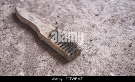 Alte, abgenutzte Stahldrahtbürste mit ausgefransten Borsten, die strukturierte Details eines robusten Werkzeugs zeigt, das bei der Bau- und Materialwartung verwendet wird. Stockfoto