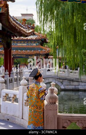 Pavillons im Beihai Park in Peking mit einer Frau in traditioneller chinesischer Hanfu-Tracht und Weidenbäumen Stockfoto