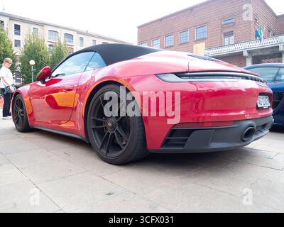 Cremona, Italien 22. August 2025 eleganter roter Porsche 911 Carrera 4S Cabriolet parkt neben zeitgenössischer Architektur und hebt das luxuriöse Design hervor Stockfoto