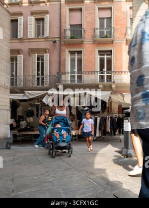 Cremona, Italien - 23. August 2025 vielfältige Familien genießen sonnige Nachmittagsspaziergänge durch den belebten Outdoor-Markt im historischen europäischen Stadtzentrum Stockfoto