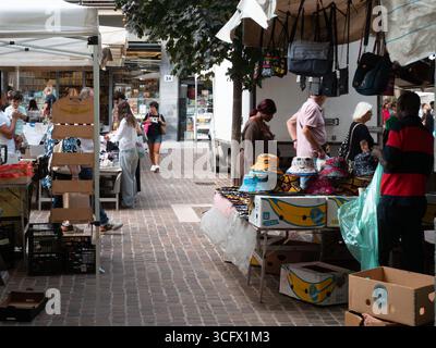 Cremona, Italien – 23. August 2025 geschäftige Outdoor-Marktszene mit verschiedenen Käufern, die an Verkaufsständen mit Waren unter sonnigem Himmel in Italien stöbern Stockfoto