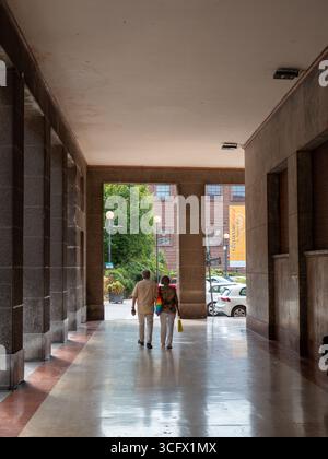 Cremona, Italien- 23. August 2025 ältere Ehepaare gehen Hand in Hand durch eine Kolonnade in einer europäischen Stadt an einem sonnigen Tag, umgeben von Architektur und Stockfoto