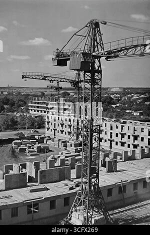 Panoramablick auf den großformatigen Bau eines neuen Paneelmikroraions in Sloviansk, ukrainische SSR, 1970er Jahre, mit schienenmontierten Turmdrehkranen und Montagearbeitern, die die industrielle Wohnungsentwicklung und das friedliche Wachstum des Donbas während der Stagnation symbolisieren Stockfoto