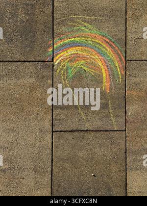 Kreidezeichnung auf dem Gehweg. Ein Regenbogen auf dem Asphalt. Aktivitäten für Kinder. Farbige Kreide im Hintergrund. Zurück zum Schulspielplatz, Kopierraum. Stockfoto