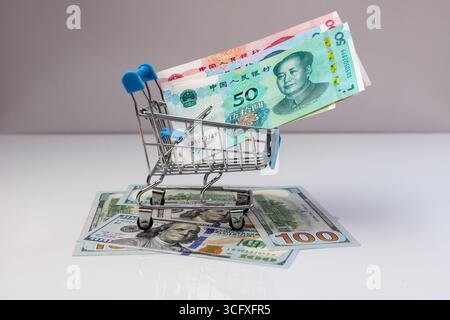 Warenkorb gefüllt mit Yuan-Banknoten auf US-Dollar. Als Symbol für globale Finanzen und Handel. Konzept des globalen Konsums. Stockfoto