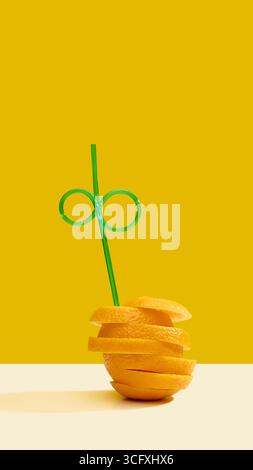 Orangefarbene Schichten, gestapelt mit grünem Stroh auf gelbem Hintergrund Stockfoto