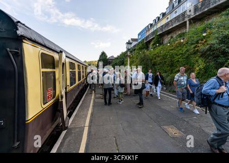 Touristen, die an einem malerischen Bahnhof in Tenby, Wales, Vereinigtes Königreich, in einer alten Dampfeisenbahn einsteigen, genießen ein nostalgisches Reiseerlebnis Stockfoto