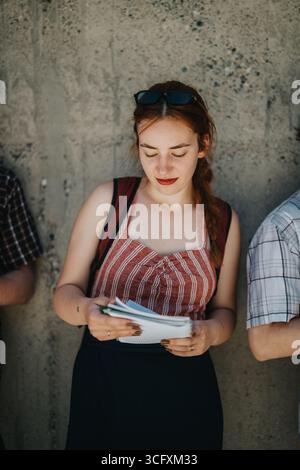 Junge Schülerin liest im Freien, hält Notizen und trägt Freizeitkleidung Stockfoto