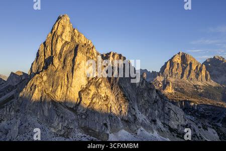 Aus der Vogelperspektive der zerklüfteten Gipfel, die in das warme Licht des Sonnenaufgangs getaucht sind, werfen schroffe Schatten über das felsige Gelände des Passo Giau, Cortina d'Ampezzo, Bell Stockfoto