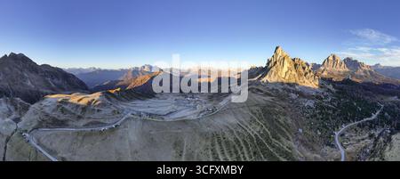 Aus der Vogelperspektive auf den Passo Giau, wo die zerklüfteten Gipfel der Berge sich im goldenen Licht vor den kühlen Schatten sonnen, Cortina d'Ampezzo, Belluno, Italien. Stockfoto