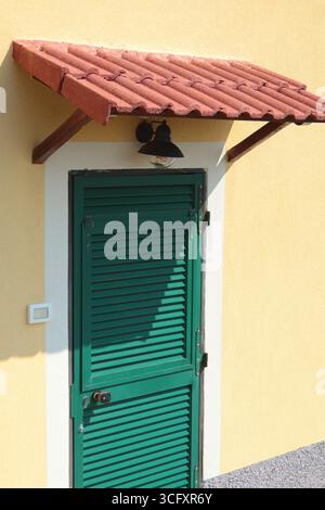 Traditionelle grüne Türen und Fenster von Ligurien. Gefliestes Vordach. Traditionelle Gebäude Italiens. Kopierbereich für Konstruktion. Stockfoto