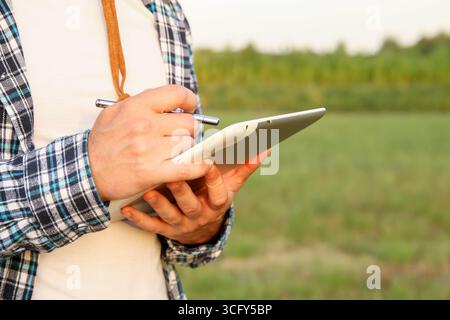 Ein Landwirt, der ein Tablet auf einem Bauernhof benutzt. Landwirt mit Tablettenlandwirtschaft AI. Datenwissenschaft für intelligente Landwirtschaft. Präzisionslandwirtschaft Stockfoto