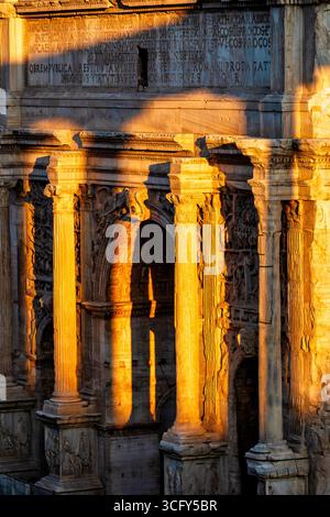 Der Schatten des Saturntempels fällt auf den Bogen des Septimius Severus bei Sonnenuntergang im Forum Romanum, Italien. Stockfoto