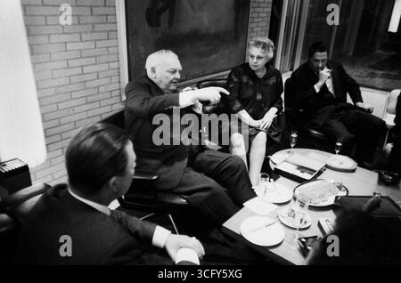 Ludwig Erhard sitzt mit weiteren Personen an einem gedeckten Tisch in einem modernen eingerichteten Raum. Neben ihm seine Ehefrau Luise Erhard. Auf dem Tisch stehen Getränke, Speisen und Zigarrenzubehör. Stockfoto