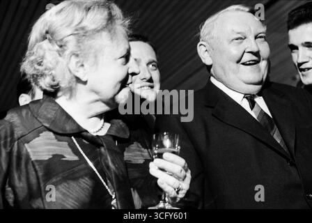 Ludwig Erhard und seine Ehefrau Luise Erhard stehen gemeinsam mit mehreren jüngeren Männern bei einem festlichen Anlass. Beide lachen, Luise Erhard hält ein Glas in der Hand. Stockfoto