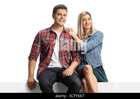 Ein junges Paar sitzt auf einer leeren Tafel isoliert auf weißem Hintergrund Stockfoto