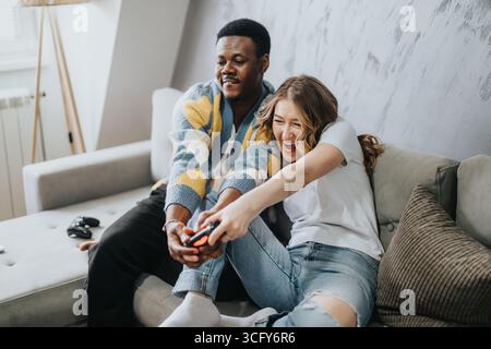 Ein vielseitiges Paar, das Videospiele genießt und zu Hause eine schöne Zeit hat Stockfoto