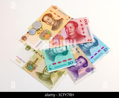 Fächerverbreitung chinesischer Yuan-Banknoten und -Münzen auf weißem Hintergrund. Stockfoto