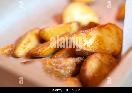 Köstlich goldene und knusprige Kartoffelscheiben, serviert in einer Fastfood-Box. Perfekt für Snacks oder Beilagen. Stockfoto