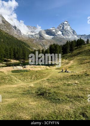 Breuil Cervinia Aosta-Tal Italien. Der majestätische Gipfel des Matterhorns ragt über dem ruhigen blauen See und grünen Wiesen Stockfoto
