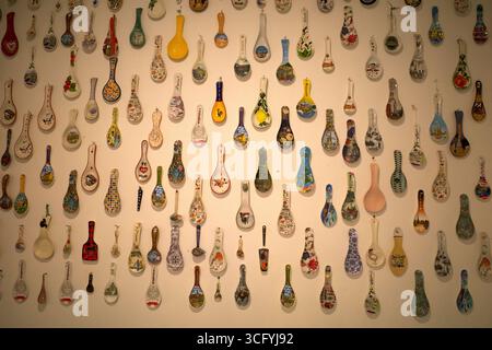 Eine Sammlung von bunten antiken Löffeln aus verschiedenen Ländern, ausgestellt an einer Wand. Stockfoto