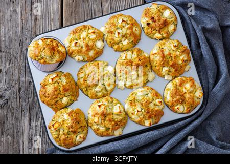 Zucchini Feta Muffins in Muffindose auf rustikalem Holztisch mit Küchentuch, horizontaler Blick von oben, nicht AI generiert, flach liegend, Nahaufnahme Stockfoto