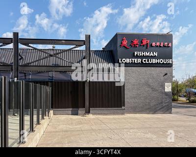 Außenansicht des Fishman Lobster Clubhouse in Scarborough, Kanada. Modernes dunkles Geschäftsgebäude mit roten Schildern, einer Terrasse im Freien und einem blauen Himmel. Stockfoto