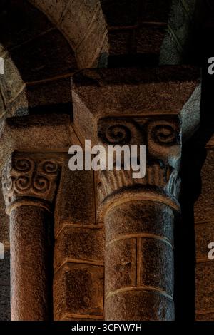 Doppelrollen oder Spiralen auf Granitkapitellen in der Kirche Saint Tudy in Loctudy, Finistère, Südwestbretagne, Frankreich, sehen auf den ersten Blick wie Blicke auf Besucher. Die Kirche aus dem 11. Und 12. Jahrhundert hat Dutzende von geschnitzten Kapitellen und ihre Säulenbasen gehören zu den reichsten in der Bretagne. Die Schnitzereien umfassen Kreuzigungsszenen, die selten auf romanischen Kapitellen zu sehen sind. Stockfoto