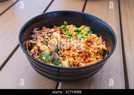 Schüssel mit Schalen in schwarzer Schüssel auf Holztisch, asiatischer Komfort Stockfoto