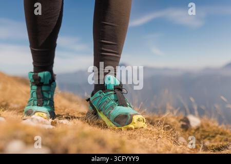 Eine Nahaufnahme der Wanderschuhe eines Menschen auf felsigem Boden in einer bergigen Landschaft bei sonnigem Wetter. Stockfoto